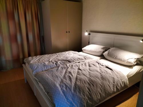 ein Schlafzimmer mit einem Bett mit weißen Laken und Kissen in der Unterkunft Silver Lotus in De Haan