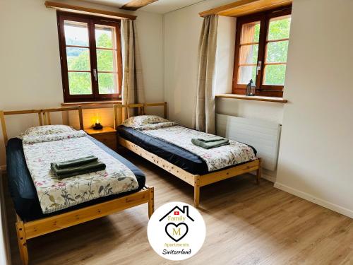 two beds in a room with two windows at Family M Apartments 15 in Kappel bei Olten