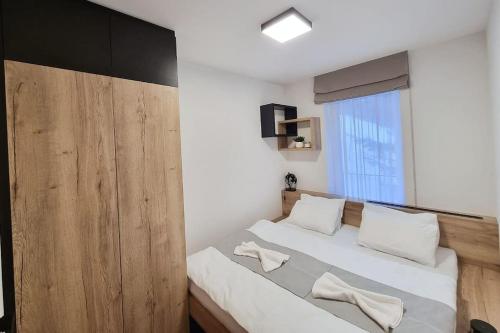 a bedroom with a bed with white pillows and a window at Apartmá v klidné lokalitě Krkonoš. in Pec pod Sněžkou