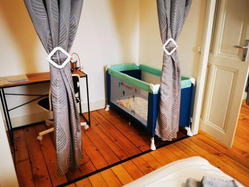 a bedroom with a crib with curtains and a wooden floor at DIAMOND appartement au centre de Genève in Geneva