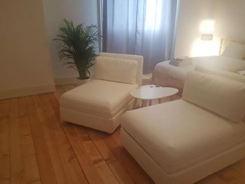 a living room with white furniture and a couch and a table at DIAMOND appartement au centre de Genève in Geneva