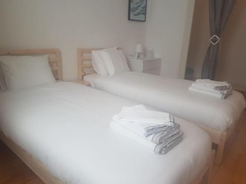 two beds in a room with white sheets and towels at DIAMOND appartement au centre de Genève in Geneva