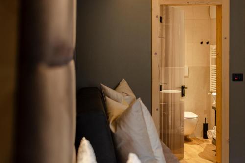 um quarto com um sofá com almofadas e uma casa de banho em Suite del Podesta' em Moena
