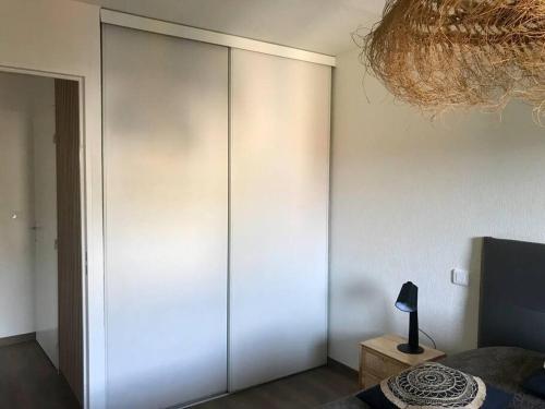a bedroom with a large white closet with a lamp on a table at T2 Beaux Arts climatisation loggia parking privé in Montpellier