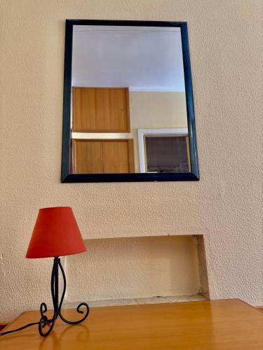 a mirror on a wall with a red lamp and a red lampshade at Innpiero in Taormina