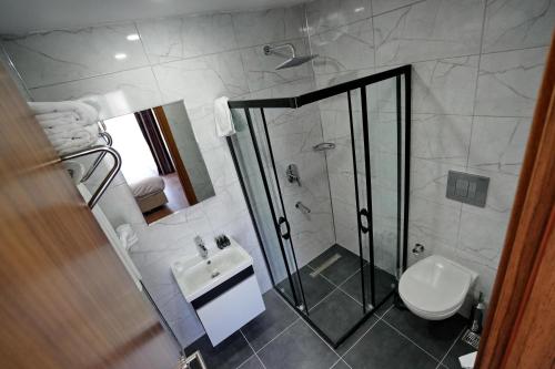 a bathroom with a shower and a toilet and a sink at Shelton Airport Hotel in Arnavutköy