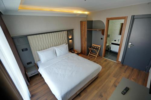 um quarto com uma grande cama branca e uma secretária em Shelton Airport Otel em Arnavutköy