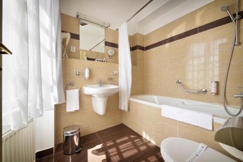 a bathroom with a sink and a tub and a toilet at Hotel Certovka in Prague
