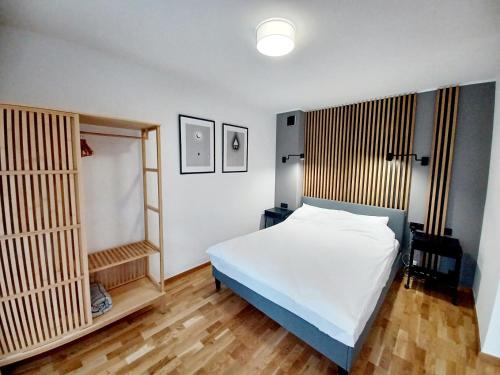 - une chambre avec un lit blanc et du parquet dans l'établissement Kolory Warmii Apartamenty Garaż Podziemny-30pln-doba, à Olsztyn