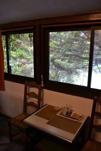 une table et des chaises dans une pièce avec deux fenêtres dans l'établissement Maison 4 km Disneyland 30 min Paris, à Esbly