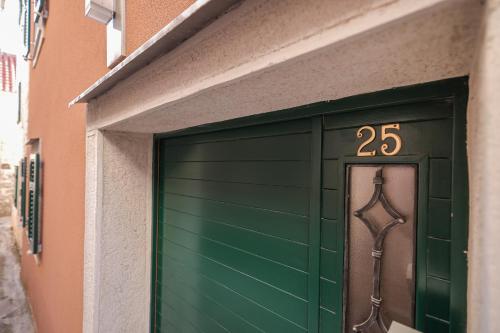 a green garage door with the number on it at Kuća dide Mate in Sveti Filip i Jakov