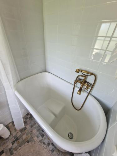 a white bath tub with a gold faucet in a bathroom at Seglarevistet 2 in Domsten