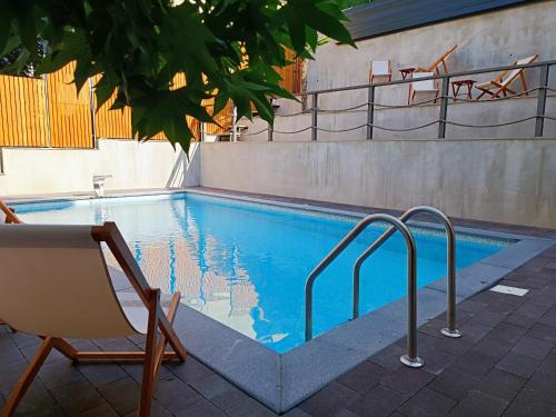 a swimming pool with a chair and a table at APARTMANI SUNNY SIDE in Vrnjačka Banja