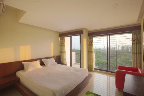 a bedroom with a bed and a large window at Hotel Orchid Blue in Ināni