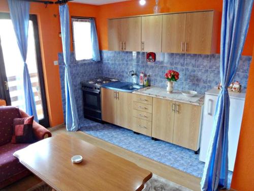 a kitchen with orange walls and wooden cabinets and a table at Apartman Milica in Foča