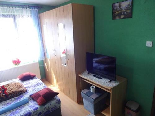 Schlafzimmer mit einem Bett und einem TV auf einem Schreibtisch in der Unterkunft Apartman Milica in Foča