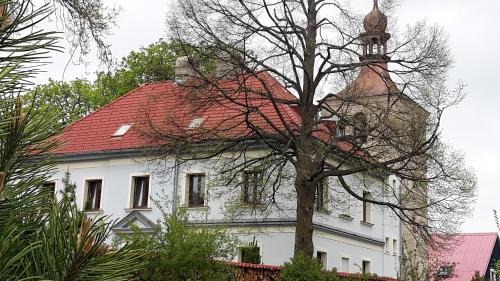 a white house with a red roof and a tree at Penzion Zvonice Hojná Voda in Horní Stropnice