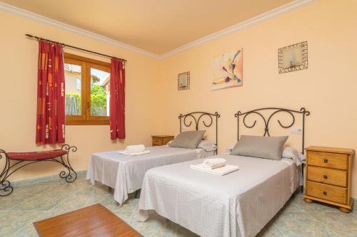 ソン・セッラ・デ・マリーナにあるVilla Son Serraの赤いカーテンが備わるドミトリールームのベッド2台分です。