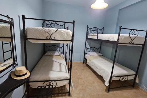 three bunk beds in a room with a hat at Amazing seafront house with private beach in Paránimfoi
