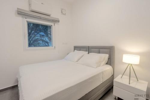 um quarto branco com uma cama branca e uma janela em Luxury Shenkin 2BR by Airsuite em Tel Aviv