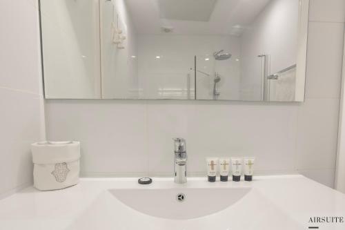 a white bathroom with a sink and a mirror at Luxury Shenkin 2BR by Airsuite in Tel Aviv