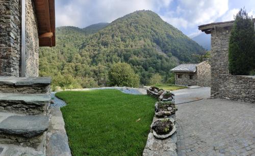 a stone house with a grassy yard with a mountain at Ai Tetti Nuovi in Roccaforte Mondovì