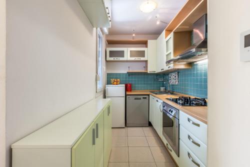 a kitchen with white cabinets and blue tiles at Hana City Apartment in Split