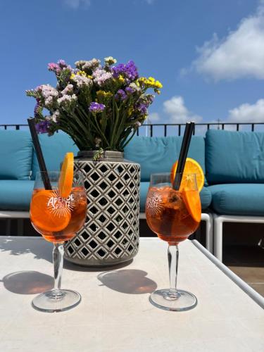 two glasses of orange juice on a table with a vase of flowers at My Travel House in Rabat