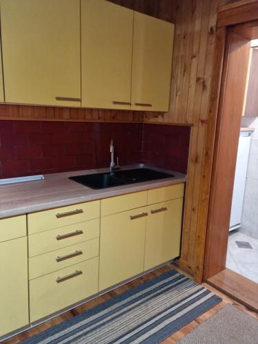 - une cuisine avec des placards jaunes et un évier dans l'établissement Počitniška hiša LIPA, à Zreče