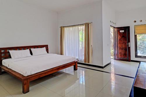 1 dormitorio con 1 cama con sábanas blancas y ventana en OYO 92706 Nadia Pansion, en Ketewel