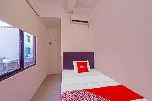 a small room with a red pillow on a bed at Super OYO 92664 Cemara Koja Residence Syariah in Jakarta