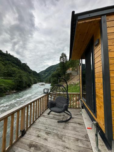 einen Stuhl auf einem Deck neben einem Fluss in der Unterkunft Nayon Tiny House in Rize