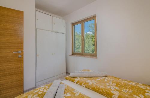 a small room with a bed and a window at Apartment Moderna Soline in Dobrinj