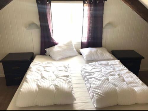 1 cama con sábanas y almohadas blancas frente a una ventana en Waterfront Cottage (Fishing Opportunities!) en Ålesund