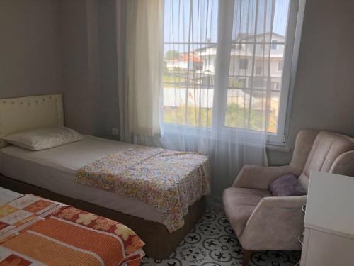 um quarto com uma cama, uma cadeira e uma janela em Doğa Evleri em Marmara