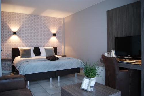 Schlafzimmer mit einem Bett, einem Schreibtisch und einem TV in der Unterkunft B&B Maison Kerkhove in Kerkhove