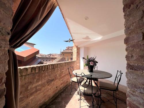 a balcony with a table and chairs on a brick wall at Il Terrazzo di Tolomei in Siena