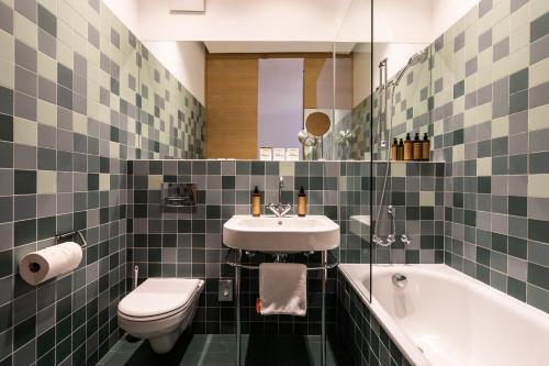 a bathroom with a sink and a toilet and a tub at Buxbaum Beletage Design & Boutique Hotel in Vienna
