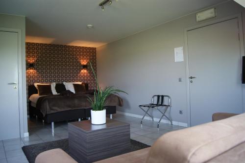 a bedroom with a bed and a couch and a table at B&B Maison Kerkhove in Kerkhove