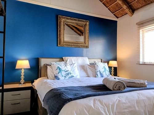 a bedroom with a blue wall and a bed with pillows at Sedgefield Lodge in Witbank