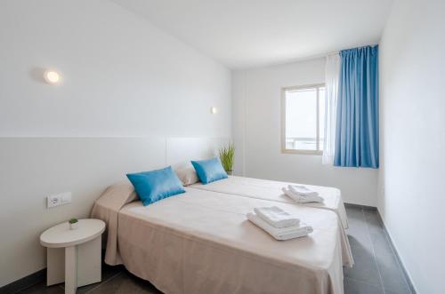two beds in a white room with blue pillows at Rentalmar Blue Beach Apartments & Pool in Salou
