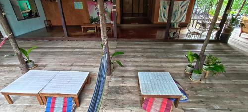 two benches and a hammock in front of a house at TA YAI HOMESTAY (ตา ยาย โฮมสเตย์) in Ko Kood
