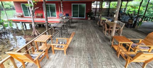 a group of tables and chairs on a wooden deck at TA YAI HOMESTAY (ตา ยาย โฮมสเตย์) in Ko Kood