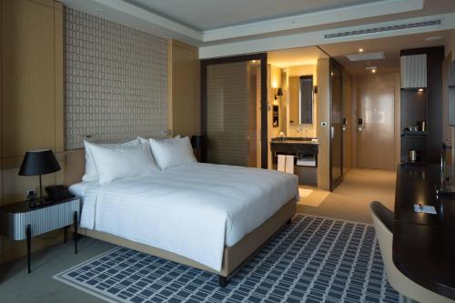 a bedroom with a large white bed and a bathroom at Skopje Marriott Hotel in Skopje
