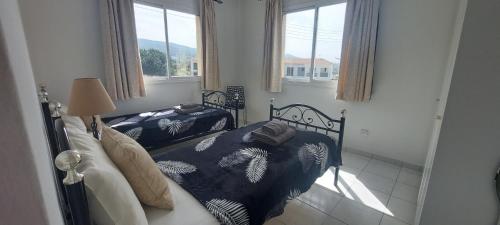 a bedroom with two beds and two windows at Spacious 2 bedroom apartment in Peyia
