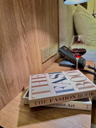 a book and a glass of wine on a table at Harmony Phnom Penh Hotel in Phnom Penh