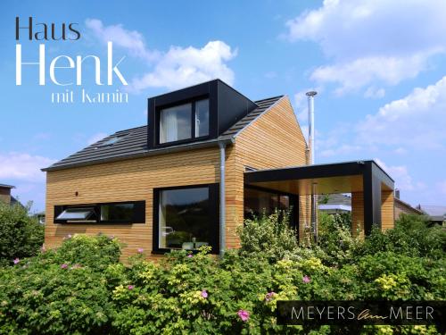 a house with a black roof on top of some bushes at Schickes Holzchalet "HENK" - mit Kamin - Ostsee Strand 500m - 4 Personen - by "Meyers am Meer" in Zierow