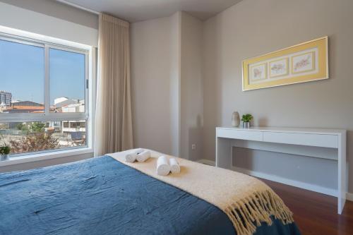 a bedroom with a blue bed with towels on it at Carolina Roomy & Modern Apartment in Porto