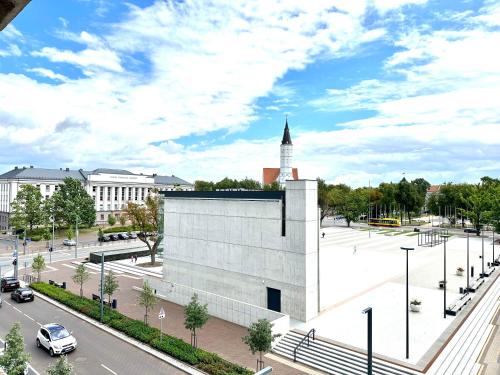 duży biały budynek z wieżą zegarową w mieście w obiekcie Butas pačiame Šiaulių miesto centre w Szawlach