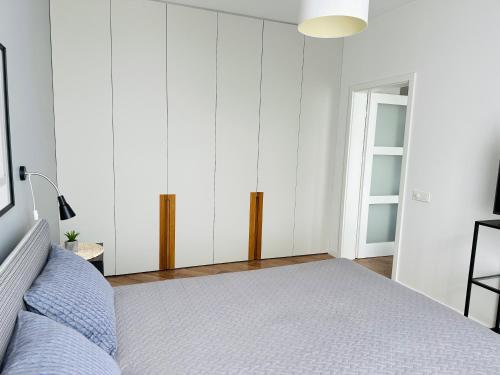 a white bedroom with a bed and a window at Butas pačiame Šiaulių miesto centre in Šiauliai